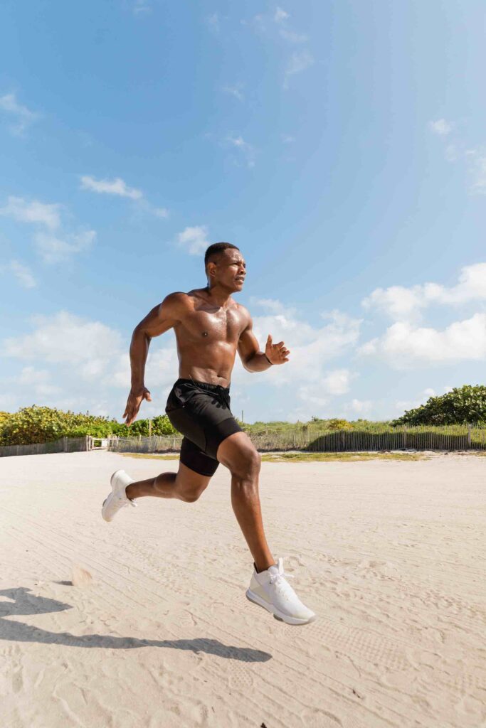 Man running on a sandy beach, showcasing fitness and an active lifestyle.